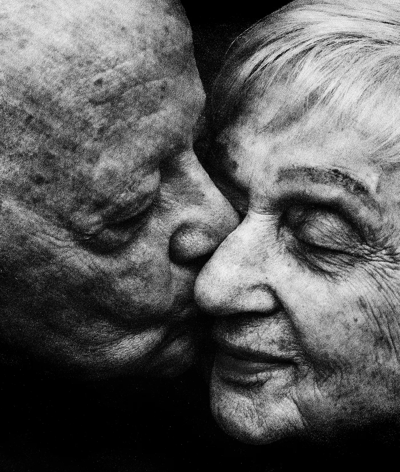 An elderly couple, eyes closed, holding each other close
